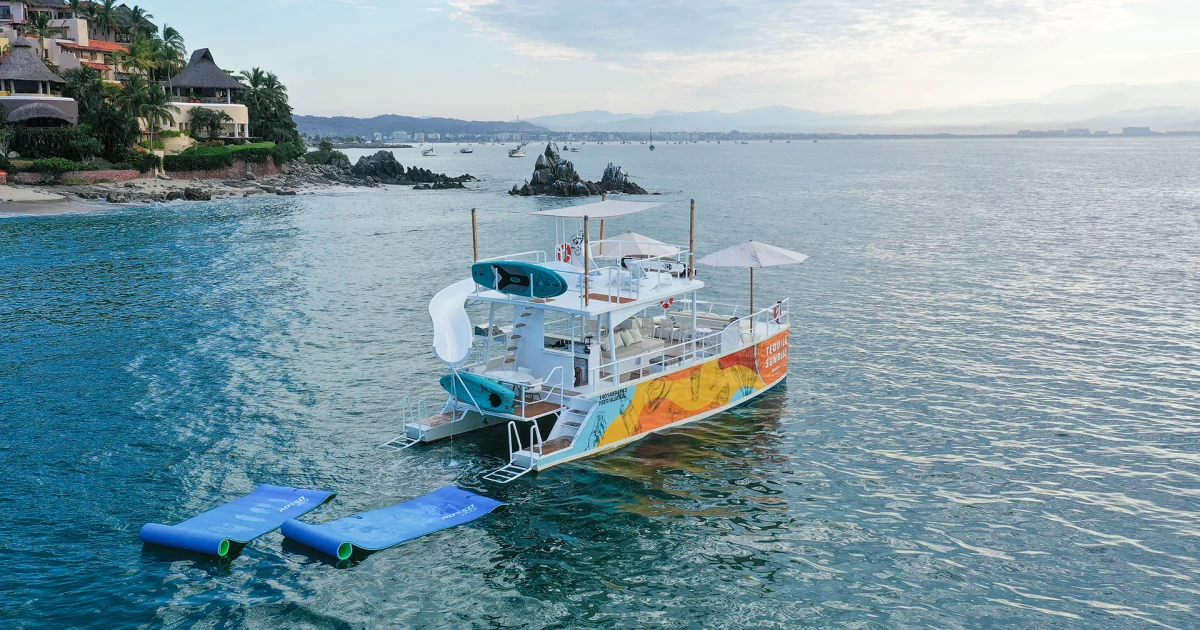 El catamarán de fiesta de 45 pies con tobogán fondeado cerca de Los Arcos en un charter de grupo en Puerto Vallarta